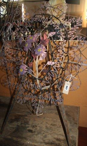An oval beaded floral display on tripod stand